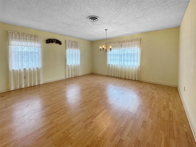 10550 Fm 215, Valley Mills, TX 76689 - empty room with a chandelier, a textured ceiling, light wood-style flooring, and baseboards
