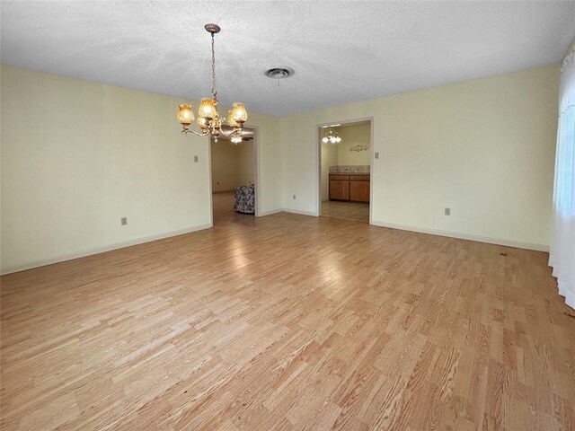 10550 Fm 215, Valley Mills, TX 76689 - spare room featuring a chandelier, light wood-style floors, baseboards, and a textured ceiling