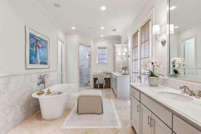 bathroom with a shower stall, ornamental molding, a freestanding tub, two vanities, and recessed lighting