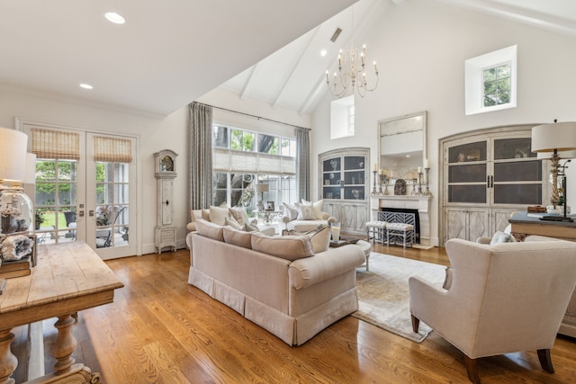 living room featuring beamed ceiling, a chandelier, a fireplace, wood finished floors, and french doors