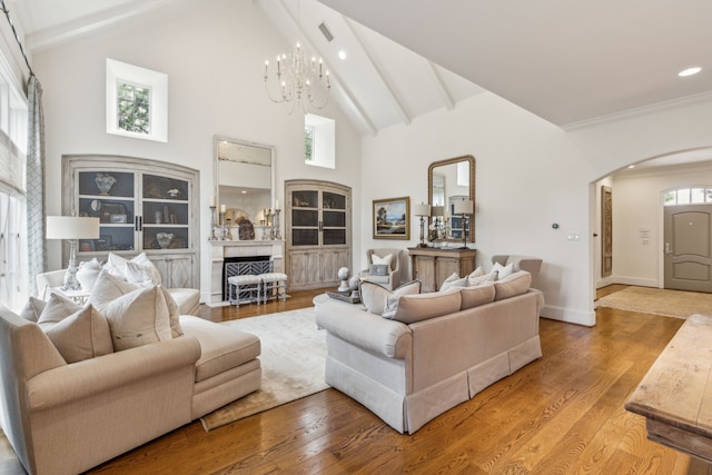 living area featuring arched walkways, a chandelier, beam ceiling, high vaulted ceiling, and light wood-style floors