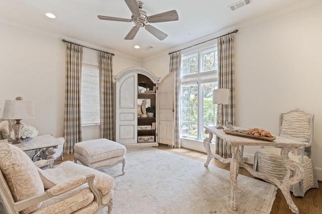 living area with wood finished floors, ornamental molding, ceiling fan, and recessed lighting