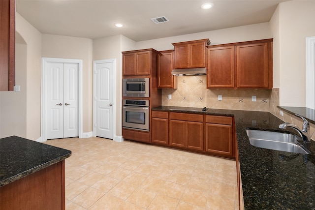 609 Racine Dr, Oak Point, TX 75068 - kitchen featuring appliances with stainless steel finishes, a sink, under cabinet range hood, tasteful backsplash, and dark stone countertops