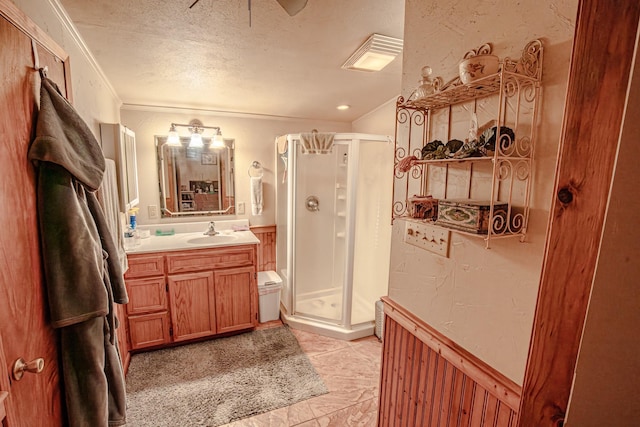 12815 N Fm 219, Dublin, TX 76446 - bathroom featuring crown molding, a stall shower, a textured ceiling, vanity, and a wainscoted wall