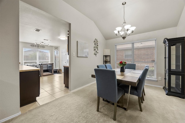dining room featuring a chandelier, light carpet, lofted ceiling, baseboards, and light tile patterned floors