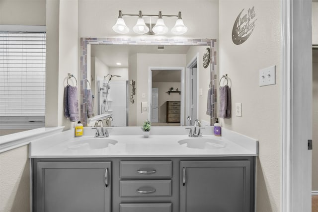 bathroom featuring double vanity, a shower, and a textured wall