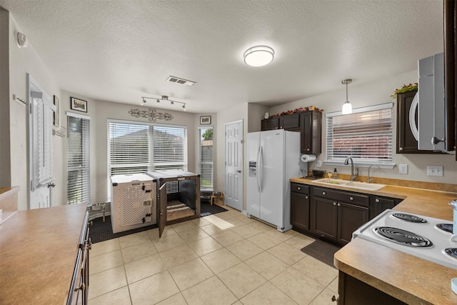 kitchen featuring white appliances, a sink, a textured ceiling, light tile patterned floors, and light countertops