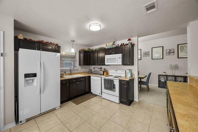 kitchen featuring white appliances, a sink, light countertops, light tile patterned floors, and baseboards