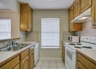 3233 S Univer Dr, Fort Worth, TX 76109 - kitchen featuring white appliances, a sink, brown cabinets, and light countertops