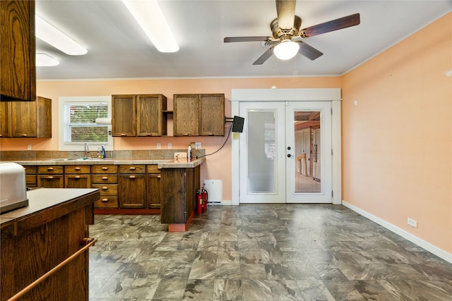 670 SE 22nd St SE, Paris, TX 75460 - kitchen featuring french doors, ceiling fan, brown cabinetry, baseboards, and ornamental molding