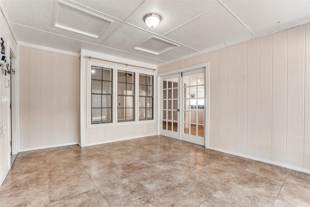 unfurnished room featuring attic access and wood walls