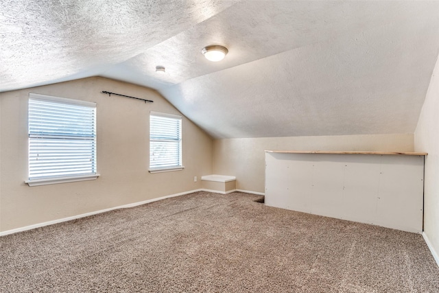 bonus room with a textured ceiling, carpet, vaulted ceiling, and baseboards