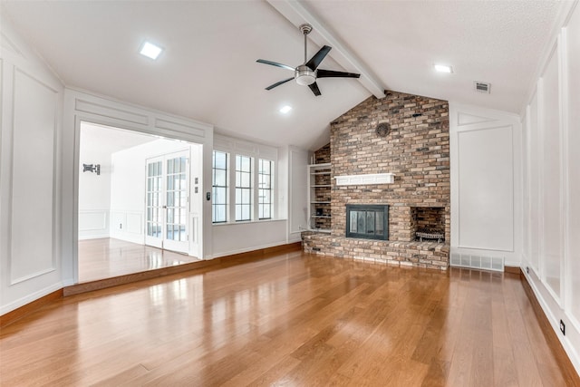 unfurnished living room featuring a decorative wall, a ceiling fan, wood finished floors, and a brick fireplace