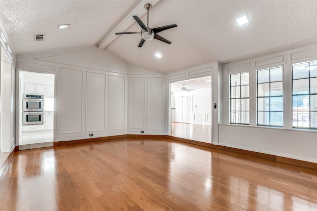 unfurnished living room with a ceiling fan, a decorative wall, light wood-style flooring, and a textured ceiling
