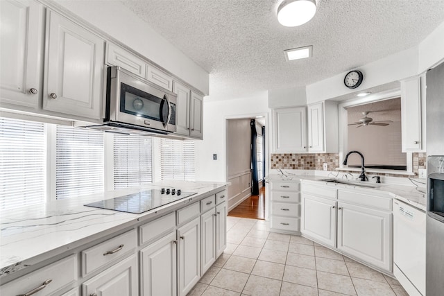 kitchen with dishwasher, stainless steel microwave, a sink, black electric cooktop, and ceiling fan