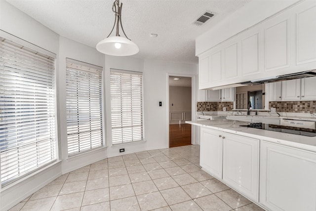 kitchen with a textured ceiling, tasteful backsplash, white cabinets, black electric cooktop, and decorative light fixtures