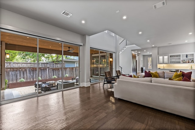 living room with recessed lighting, wood finished floors, and bar