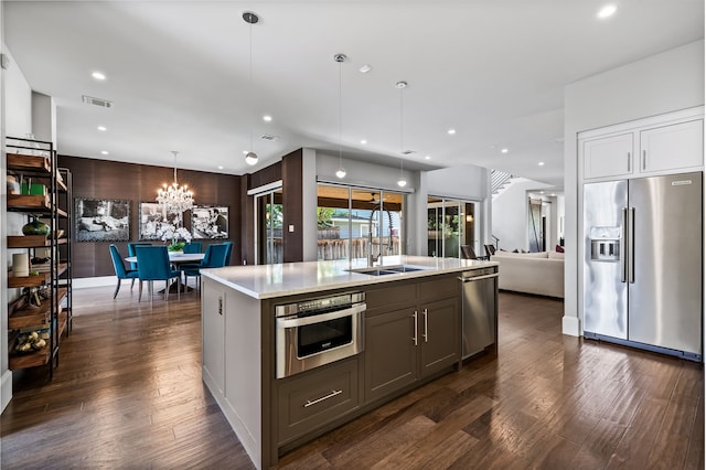 kitchen with stainless steel appliances, light countertops, a sink, dark wood finished floors, and open floor plan