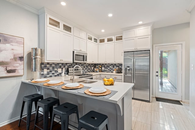 1219 Haines Ave, Dallas, TX 75208 - kitchen featuring appliances with stainless steel finishes, a peninsula, tasteful backsplash, light countertops, and a kitchen bar