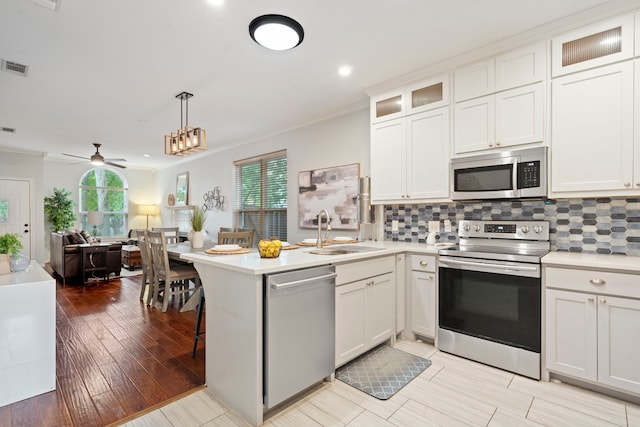 1219 Haines Ave, Dallas, TX 75208 - kitchen featuring stainless steel appliances, a peninsula, open floor plan, ornamental molding, and light countertops