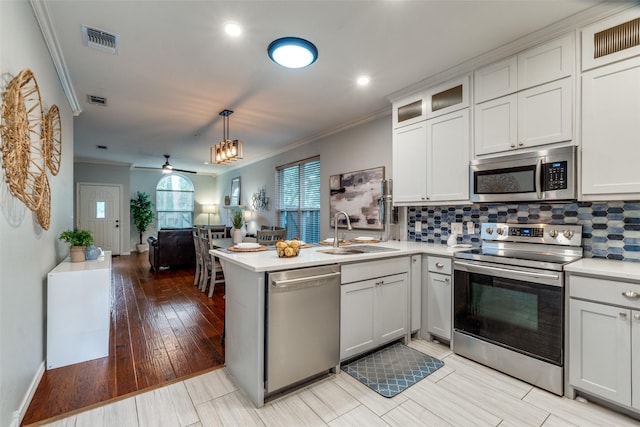 1219 Haines Ave, Dallas, TX 75208 - kitchen featuring stainless steel appliances, a peninsula, crown molding, light countertops, and backsplash