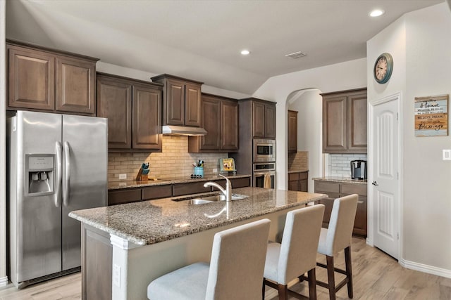 3626 Green Bluff Ct, Midlothian, TX 76065 - kitchen with stainless steel appliances, under cabinet range hood, a sink, light stone countertops, and light wood finished floors