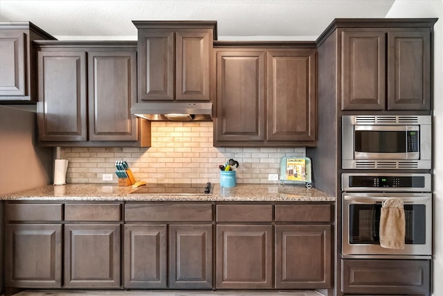 3626 Green Bluff Ct, Midlothian, TX 76065 - kitchen with stainless steel appliances, under cabinet range hood, backsplash, and light stone countertops