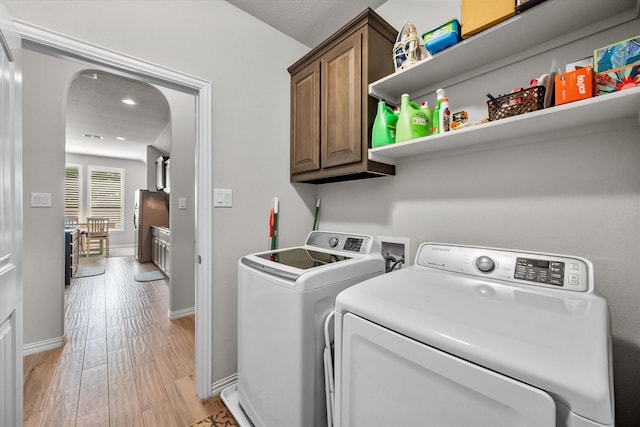 3626 Green Bluff Ct, Midlothian, TX 76065 - washroom featuring cabinet space, washing machine and clothes dryer, arched walkways, light wood-style flooring, and baseboards