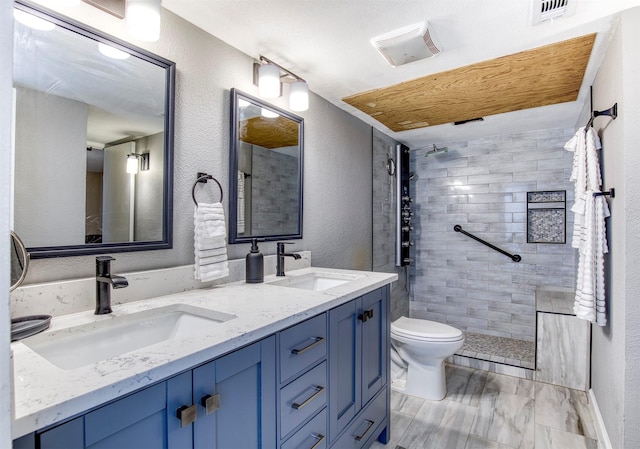 4626 Nervin St, The Colony, TX 75056 - bathroom with toilet, tiled shower, a textured wall, and double vanity