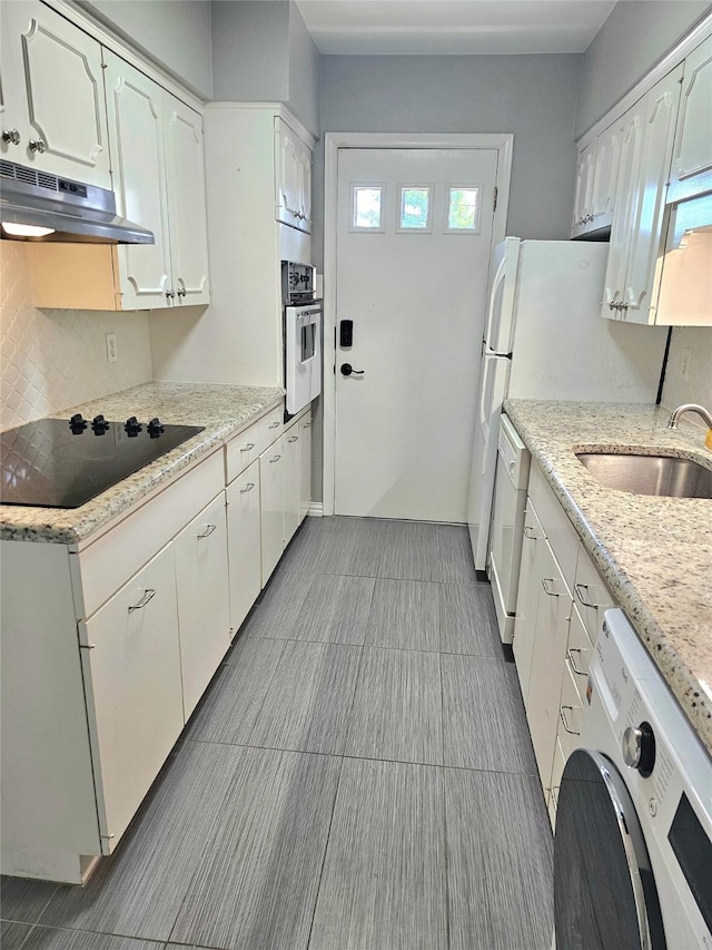 kitchen with washer / dryer, under cabinet range hood, stainless steel oven, black electric cooktop, and dishwasher