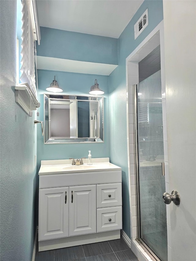 bathroom with a shower stall, vanity, tile patterned flooring, and baseboards