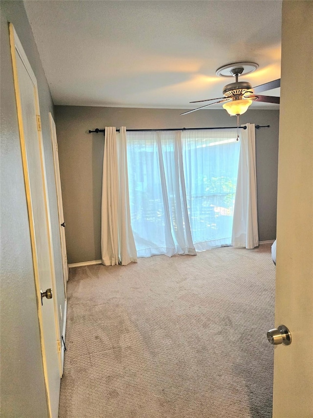 empty room featuring carpet flooring, healthy amount of natural light, and ceiling fan