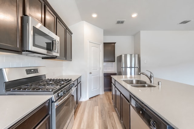 1316 Renoir Dr, Little Elm, TX 75068 - kitchen with stainless steel appliances, a sink, dark brown cabinetry, light wood-style floors, and light countertops