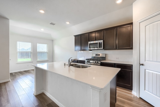 1316 Renoir Dr, Little Elm, TX 75068 - kitchen with stainless steel appliances, a sink, decorative backsplash, light wood-style floors, and dark brown cabinets