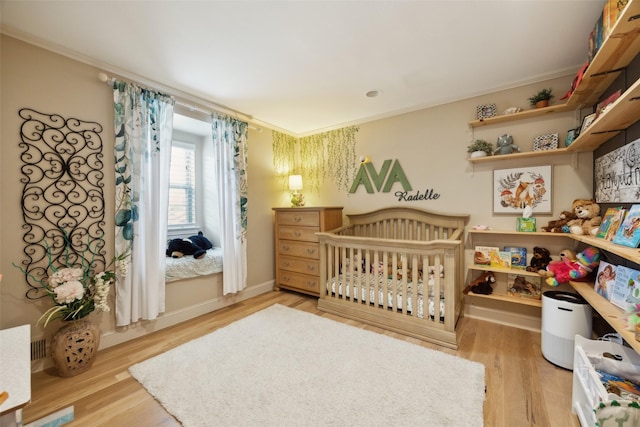 7008 Joyce Way, Dallas, TX 75225 - bedroom with light wood-style flooring, ornamental molding, and a nursery area
