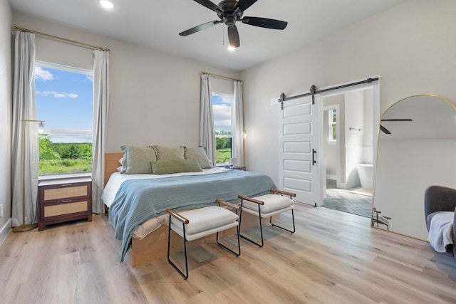 bedroom featuring a barn door, multiple windows, light wood-type flooring, a ceiling fan, and recessed lighting