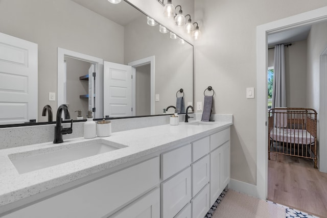 full bath with double vanity, baseboards, and wood finished floors