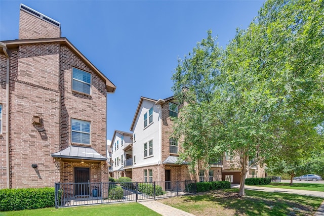 4100 Emerson Ave Unit 8, University Park, TX 75205 - view of front of house featuring brick siding, a standing seam roof, fence, and metal roof