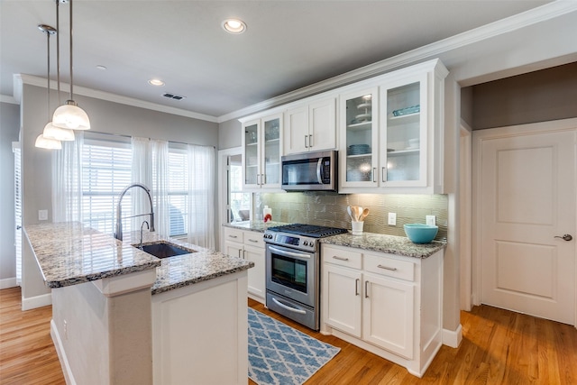 4100 Emerson Ave Unit 8, University Park, TX 75205 - kitchen featuring appliances with stainless steel finishes, ornamental molding, a sink, decorative backsplash, and an island with sink