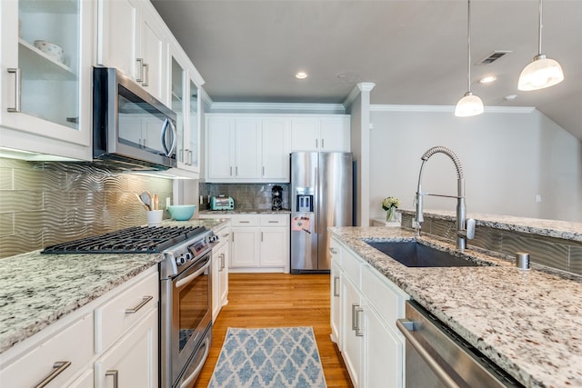 4100 Emerson Ave Unit 8, University Park, TX 75205 - kitchen with appliances with stainless steel finishes, a sink, ornamental molding, decorative light fixtures, and light wood-style floors