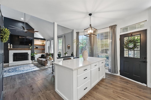 4524 Rosedale Dr, Grand Prairie, TX 75052 - kitchen featuring dark wood finished floors, white cabinetry, ceiling fan, a brick fireplace, and vaulted ceiling