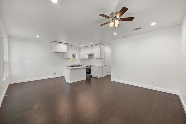 710 E 3rd Ave, Corsicana, TX 75110 - unfurnished living room with a ceiling fan, baseboards, a sink, dark wood-style flooring, and recessed lighting