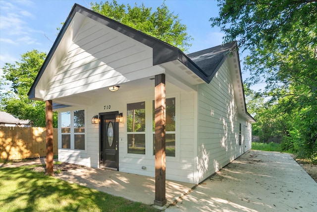 710 E 3rd Ave, Corsicana, TX 75110 - view of front facade featuring fence, a shingled roof, and a patio area