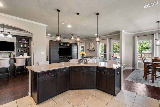 958 Prairie Timber Rd, Burleson, TX 76028 - kitchen featuring open floor plan, ornamental molding, light tile patterned floors, light stone countertops, and a kitchen island