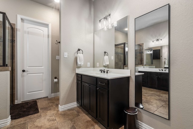 958 Prairie Timber Rd, Burleson, TX 76028 - bathroom with a shower stall, two vanities, stone tile flooring, baseboards, and a textured wall
