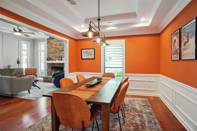 731 Falcon Ln, Coppell, TX 75019 - dining area featuring dark wood-type flooring, a tray ceiling, ornamental molding, a fireplace, and ceiling fan