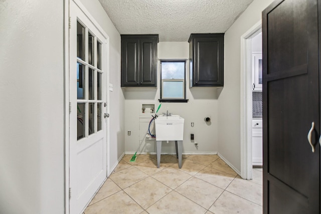 611 Buffalo Dr, Arlington, TX 76013 - washroom featuring cabinet space, hookup for a washing machine, light tile patterned floors, a textured ceiling, and baseboards