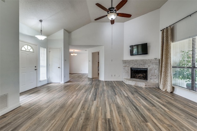 1404 Chicota Dr, Plano, TX 75023 - unfurnished living room featuring wood finished floors, a fireplace, a ceiling fan, high vaulted ceiling, and a chandelier