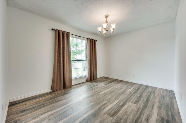 1404 Chicota Dr, Plano, TX 75023 - unfurnished room with a chandelier, wood finished floors, a textured ceiling, and baseboards