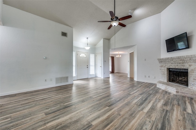 1404 Chicota Dr, Plano, TX 75023 - unfurnished living room with a ceiling fan, a fireplace, wood finished floors, a chandelier, and a textured ceiling